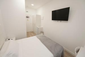 a white bedroom with a bed and a flat screen tv at Pension MD in San Sebastián