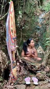 una mujer sentada en una bañera en el bosque en Casa Oásis: Requinte, Paz e Conforto na Natureza, en Atibaia