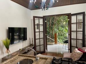 cocina con fregadero y TV en la pared en Casa Oásis: Requinte, Paz e Conforto na Natureza, en Atibaia