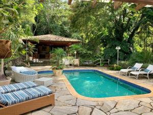 una piscina in un cortile con sedie e tavolo di Casa Oásis: Requinte, Paz e Conforto na Natureza ad Atibaia
