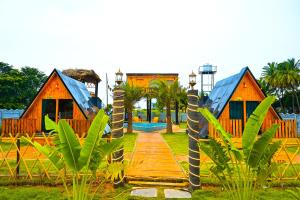 a wooden walkway in front of houses with palm trees at cebos tranquil in Hyderabad