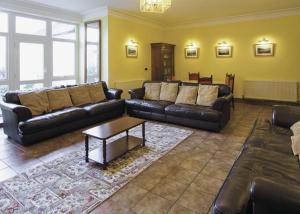 a living room with leather couches and a coffee table at Penbryn Mynach Holiday Cottage in Barmouth