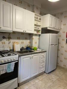 Una cocina con gabinetes blancos, estufa y refrigerador. en Hermoso y amplio departamento, en Buenos Aires 2 fotos más