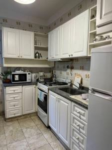 Una cocina con gabinetes blancos y un horno de estufa. en Hermoso y amplio departamento, en Buenos Aires