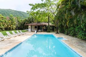 a swimming pool with chairs and a house at Chalé Aconchegante na Praia da Tabatinga in Caraguatatuba