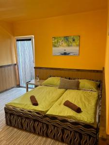 1 dormitorio con 1 cama grande y pared amarilla en Vakáció Üdülő, en Révfülöp