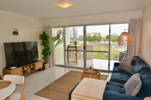 sala de estar con sofá azul y TV de pantalla plana en City Stadium One Bedroom Luxe en Townsville