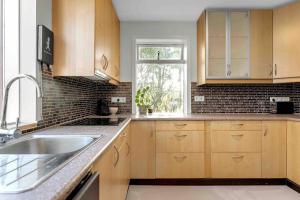 uma cozinha com armários de madeira, um lavatório e uma janela em Bright and Beautiful House em Reykjavík
