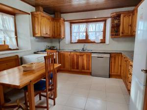 una cocina con armarios de madera, mesa y fregadero en Cal Pujol by Rural House, en Toloríu 29 fotos más