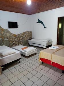 a bedroom with three beds and a dolphin on the wall at Pousada dos Arcos e Condomínio in Conde