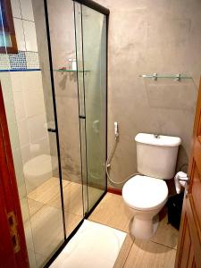 a bathroom with a toilet and a glass shower at Pousada Tulipane Florianopolis in Florianópolis