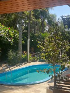 a swimming pool in a yard with a tree at Pousada Tulipane Florianopolis in Florianópolis