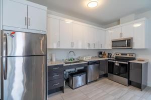 a kitchen with white cabinets and a stainless steel refrigerator at Spacious & Stylish Apt #1 with AC in Halifax