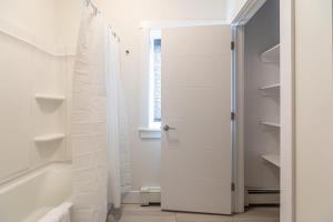 a white bathroom with a shower and a white door at Spacious & Stylish Apt #1 with AC in Halifax