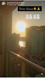 a view of a city with the setting sun from a window at Apart° Grande Lar in Guarapari