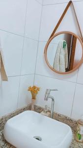 La salle de bains est pourvue d'un lavabo blanc et d'un miroir. dans l'établissement Apart° Grande Lar, à Guarapari