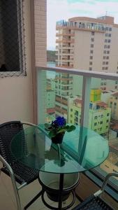 a glass table with a vase with blue flowers on it at Apart° Grande Lar in Guarapari
