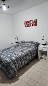 ein Schlafzimmer mit einem Bett und zwei Nachttischen mit Lampen in der Unterkunft Departamento Pichincha in Rosario