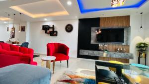 a living room with red chairs and a flat screen tv at Gold Crest Luxurious Apartments DHA Lahore by LMY in Lahore