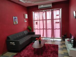 a living room with a black couch and a red wall at VILLA HAJAH RUGAYAH BAKRI MUAR in Muar