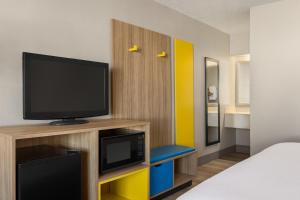 una camera con letto e televisore su un armadio di Days Inn by Wyndham Cocoa Beach Port Canaveral a Cocoa Beach