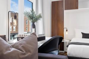 um quarto de hotel com um sofá e uma cama e uma janela em Liv MTL MTL em Montreal