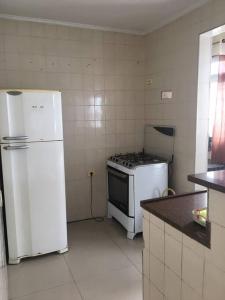 eine Küche mit einem Herd und einem weißen Kühlschrank in der Unterkunft Apto a dois quarteirões da praia da Enseada in Guarujá