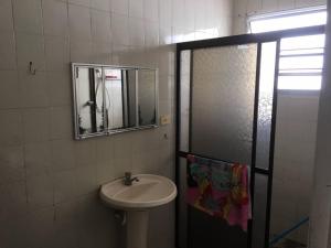 ein Bad mit einem Waschbecken und einem Spiegel in der Unterkunft Apto a dois quarteirões da praia da Enseada in Guarujá