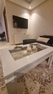 een woonkamer met een tafel en een tv aan de muur bij Appart familial chic & confort in Kenitra