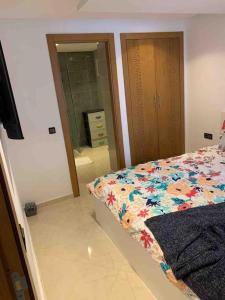 een slaapkamer met een bed en een badkamer met een spiegel bij Appart familial chic & confort in Kenitra