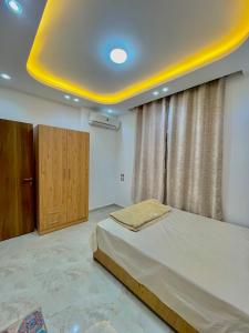een slaapkamer met een bed en een geel plafond bij Masa Hotel in Mansoura
