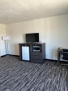 a room with a tv and a cabinet with a microwave at Super 8 by Wyndham Grand Island in Grand Island