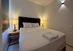 麥德林的住宿－Hotel Opera, Centro Medellín, Entertainment,Y Bar, Solo Adultos，一间卧室配有一张带两盏灯的大型白色床。