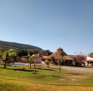 a group of houses with palm trees in a field at Pousada e restaurante Jardim do Cerrado MT in Estivado