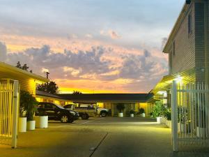 a parking lot in front of a building with a sunset at Angel's Rest Motel in Moree
