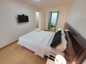 1 dormitorio con 1 cama blanca y TV de pantalla plana en Espacio Luxury Apartments- Bolivar 02, en Lima