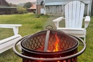 a fire pit in a yard with two white chairs at Bears Valley Inn -Peaceful, Pet Friendly Family Getaway, Less than 15 min to Attractions, with Game Room, Fire Pit & BBQ, Easy, Flat Roads in Sevierville +25 photos