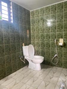 a bathroom with a toilet and a green tiled wall at Holiday home in Sylhet (Kasobir) in Kilsby