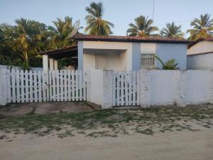 una cerca blanca frente a una casa en Casa confortável em Estancia en Estância