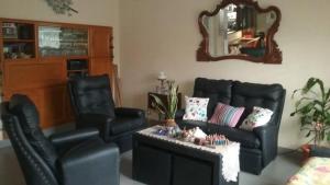 a living room with two chairs and a couch and a mirror at MIRAMAR CHALET in Miramar