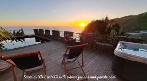 una terraza con 2 sillas y el océano al atardecer en Castelo do Mar, Madeira, en Tábua