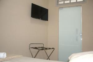 1 dormitorio con TV en la pared y silla en Pé da Serra Hotel, en Resende