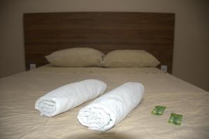 a bed with two rolls of towels on it at Pé da Serra Hotel in Resende