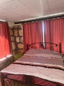 Bett in einem Zimmer mit roten Vorhängen in der Unterkunft Al-Karak Countryside and hotel in Ad Dimnah