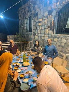 Eine Gruppe von Menschen, die an einem Tisch sitzen und Essen essen. in der Unterkunft Al-Karak Countryside and hotel in Ad Dimnah