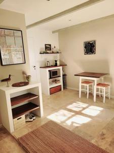 a living room with a table and a table and a kitchen at La maison blanche Intra-Muros Free parking in Aigues-Mortes