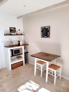 a kitchen with a wooden table and a microwave at La maison blanche Intra-Muros Free parking in Aigues-Mortes