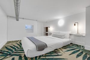 a white bedroom with a large bed and a rug at LiV MTL Main in Montréal +277 photos