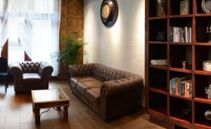 a living room with a leather couch and a book shelf at Hotel Columbus in Kraków