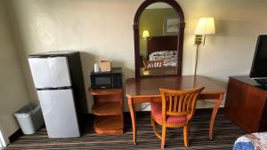Habitación con escritorio, nevera, mesa y sillas. en Gulf Way Inn Clearwater en Clearwater